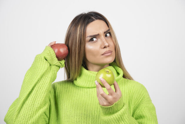 肖像身穿绿色t恤的年轻女子头顶举着两个苹果食物女性健康