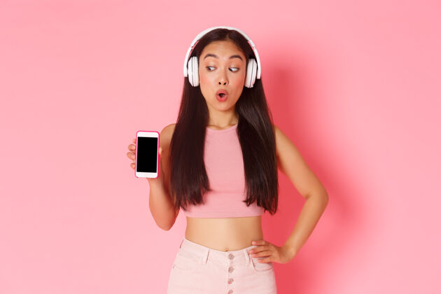 展示屏幕一个戴着耳机听音乐的富有表情的年轻女子时尚音乐亚洲