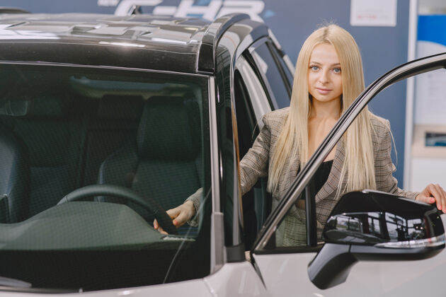 开朗汽车沙龙里的女士买车的女士穿着棕色西装的优雅女士衣服经销商年轻人