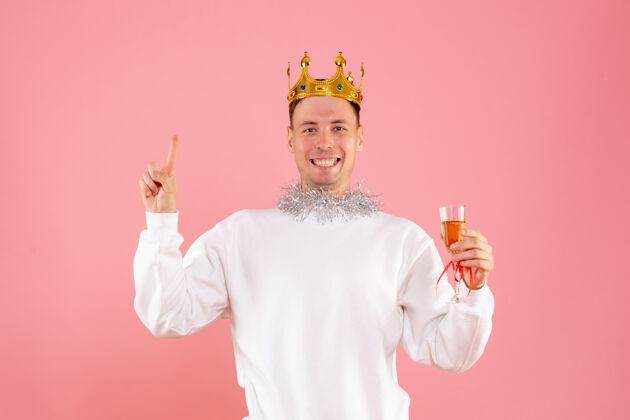 男性前视图的年轻人庆祝圣诞节与饮料上的粉红色墙壁快乐庆祝时尚