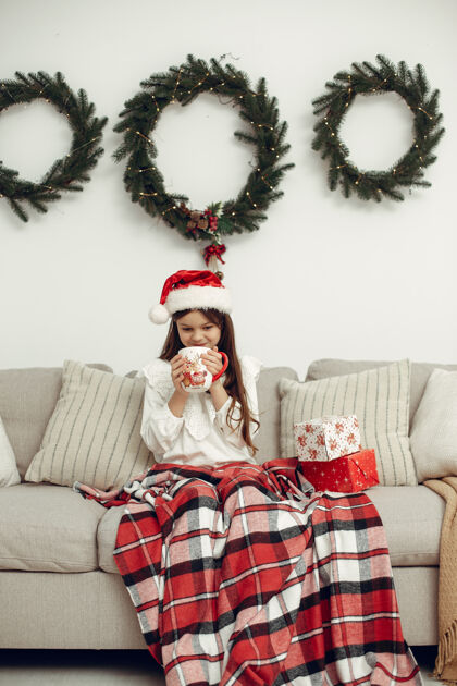 年轻穿白色毛衣的孩子坐在圣诞树旁的女儿睡衣小盒子
