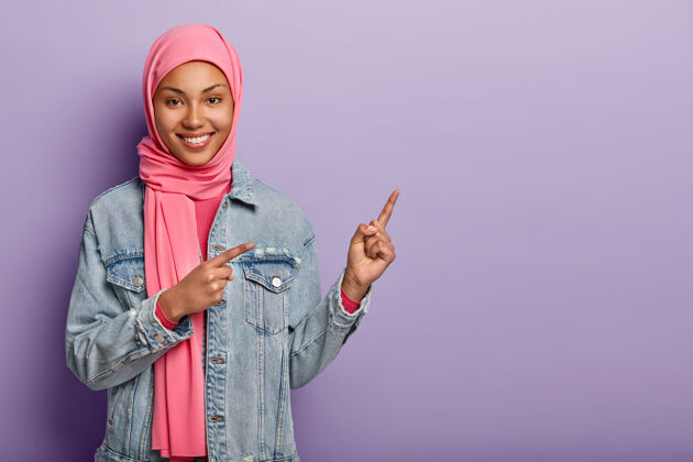 摆姿势往那边看很高兴漂亮的阿拉伯女人指对了促销头巾宗教