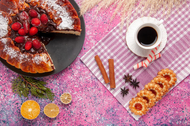 铅笔俯瞰美味的巧克力蛋糕配饼干和一杯茶在浅粉色的桌子上饼干甜甜的甜点蛋糕烤馅饼烘焙茶甜点
