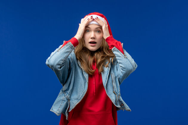 人物正面图：年轻女性 戴着淡蓝色背景的红色圣诞帽微笑浅蓝色年轻人