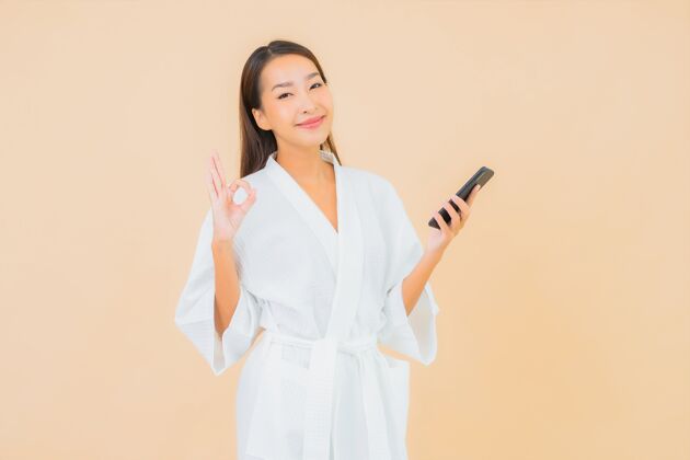 青少年用米黄色智能手机描绘美丽的亚洲年轻女子现代智能手机通话