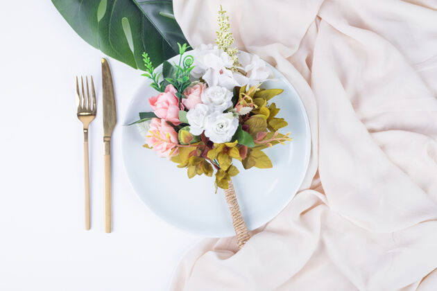 叶子玫瑰花束 餐具和盘子放在白色的表面上玫瑰人造赝品