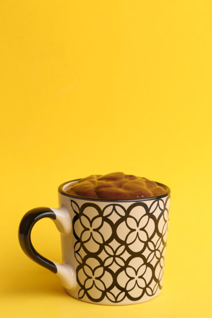 新鲜黄色背景上一杯热巧克力的垂直镜头杯子背景糖