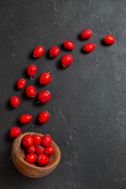 甜味新鲜的红色山茱萸浆果倒在黑色的棕色碗里的垂直视图可食木本植物灌木