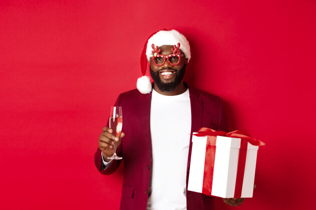 男性圣诞节戴着派对眼镜和圣诞帽的英俊的非洲裔美国人肖像快乐庆祝