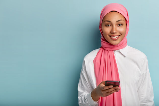 乐观高兴的妇女使用手机社交 在网上聊天中给予回复 在社交网络中发布一些东西手机头巾围巾
