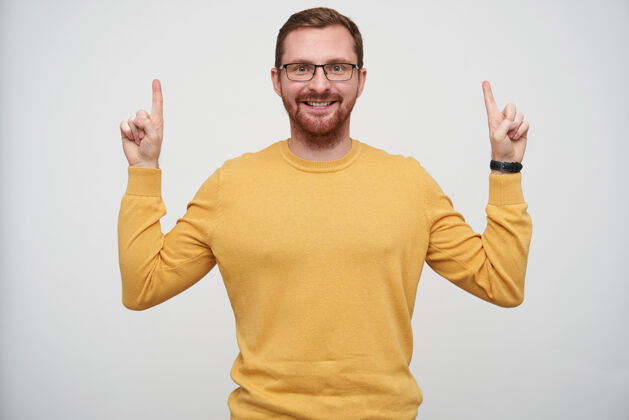 30多岁一幅快乐的年轻黑发胡子男人的画像 他戴着眼镜 食指向上 面带微笑 穿着芥末套头衫穿着好男人
