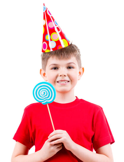 T恤微笑的男孩穿着红色t恤 戴着派对帽 手里拿着彩色糖果-白色隔离高兴衬衫轮毂