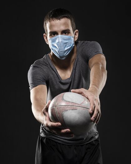 竞技男橄榄球运动员带着医用面罩拿着球锦标赛面罩锦标赛