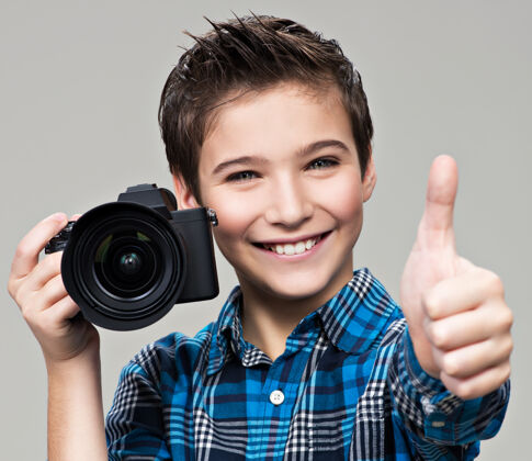 拇指男孩用相机拍照快乐有趣的男孩用单反相机显示拇指向上拇指向上摄影师拍摄