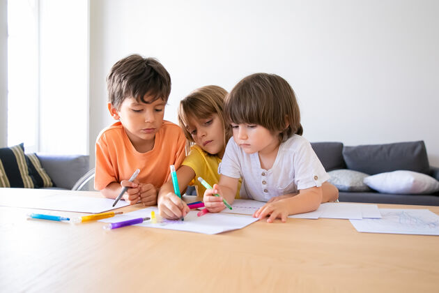 男孩有思想的孩子们在客厅用马克笔画画白种人可爱的男孩和金发女孩坐在桌子旁 在纸上画画 一起玩耍童年 创造力和周末的概念生活床单年轻