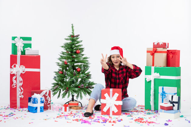 人年轻女子围坐在礼物和白色墙上的小圣诞树前的视图冬天节日圣诞