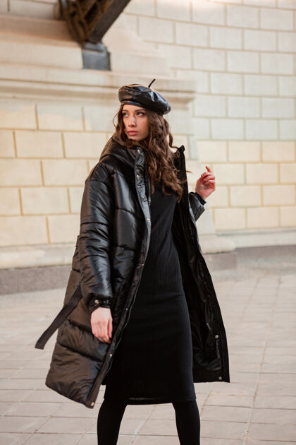 优雅时尚女人摆出冬秋时尚潮流黑色羽绒服和皮帽贝雷帽在美丽老街街头风格城市服装