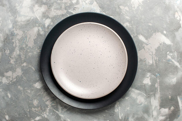 器具黑色圆形空板顶视图 灰色表面上有白色板煎锅饮料锅