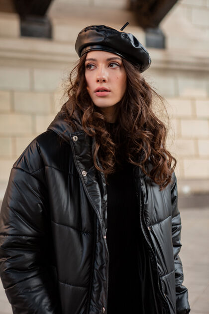 服装时尚女人摆出冬秋时尚潮流黑色羽绒服和皮帽贝雷帽在美丽老街服装户外风格