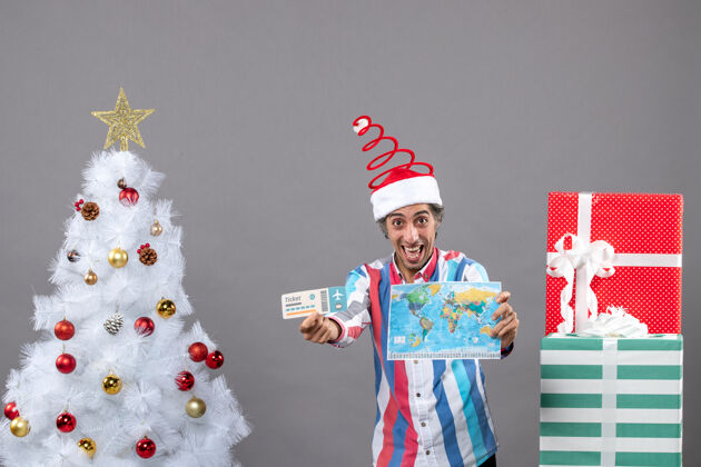 帽子前方是手持世界地图和旅行票的圣诞快乐男人微笑男人