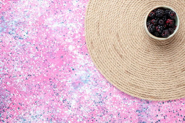 白色在粉红色桌子上的白色小锅里俯瞰新鲜的黑莓水果色少量新鲜