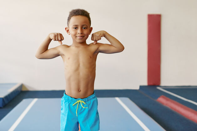 健康室内拍摄的英俊的非洲裔美国男孩与运动的身体和强大的手臂训练在健身中心年轻欢快手臂