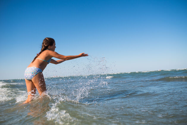 有趣在一个阳光明媚的夏日里 活泼快乐的小女孩在喧闹的海浪中嬉戏带着孩子的海上度假理念暑假美丽飞溅