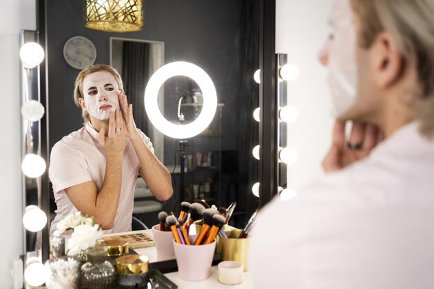 化妆品男人化妆化妆在镜子里涂上面膜时尚表情迷人