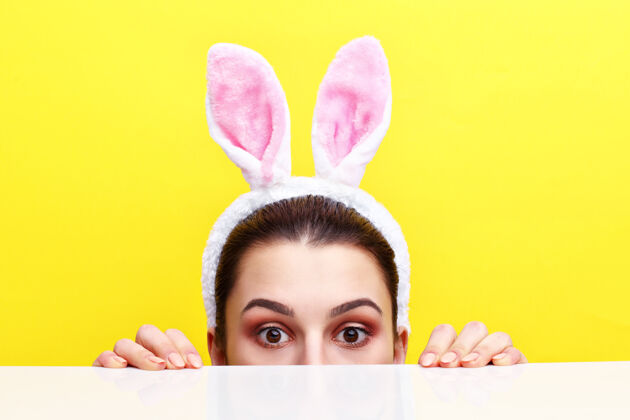 眼睛一个戴着兔子耳朵的快乐年轻女子的摄影棚镜头兔子庆祝可爱