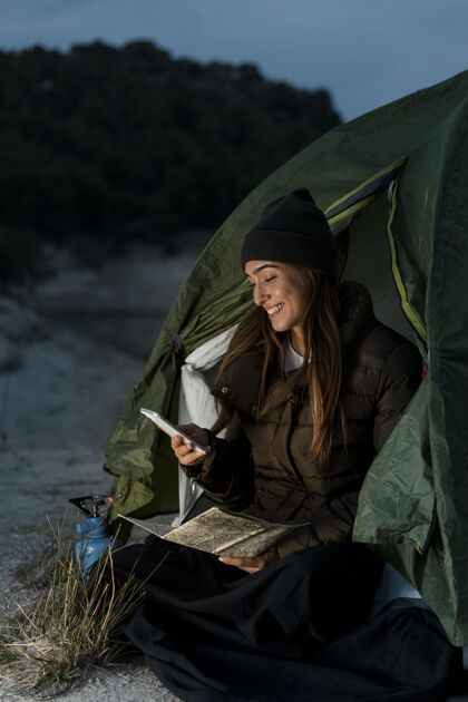 旅行女人露营和使用手机露营旅行探险