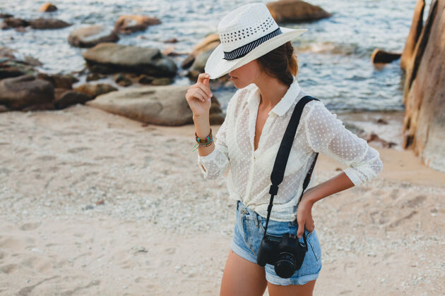帽子在亚洲度暑假的年轻漂亮的时髦女人 在热带海滩上放松 数码相机 随意的波西米亚风格 海洋风景 苗条的棕褐色身体 独自旅行肖像自由散步