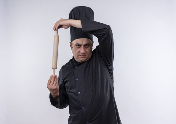 大头针身着厨师制服的中年男厨师手拿擀面杖站在隔离的白色墙壁上 留有复制空间滚制服厨师