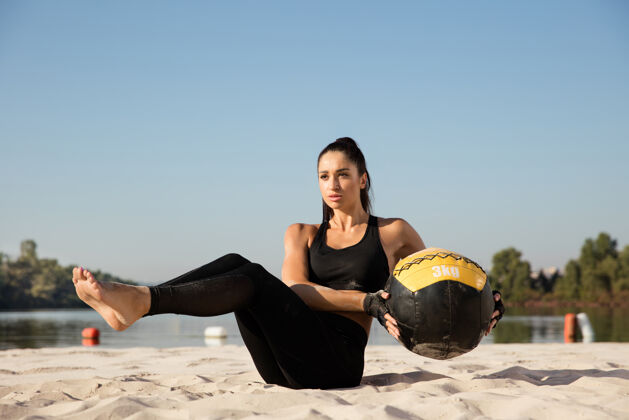 教练年轻健康的女子在沙滩上用球训练上身女人海滩帅哥