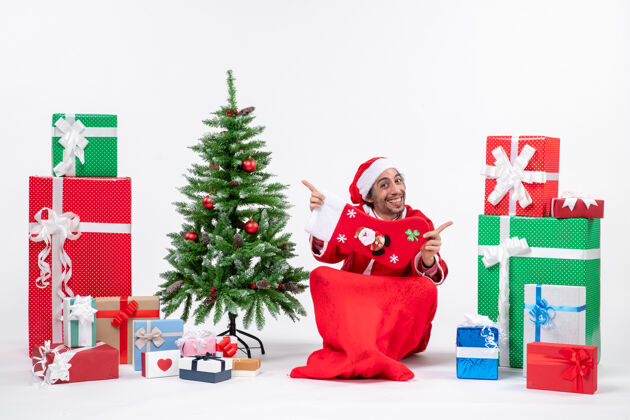 盒子圣诞老人坐在地上 在礼物和装饰过的圣诞树旁展示圣诞袜子 这是新年的气氛坐地圣诞