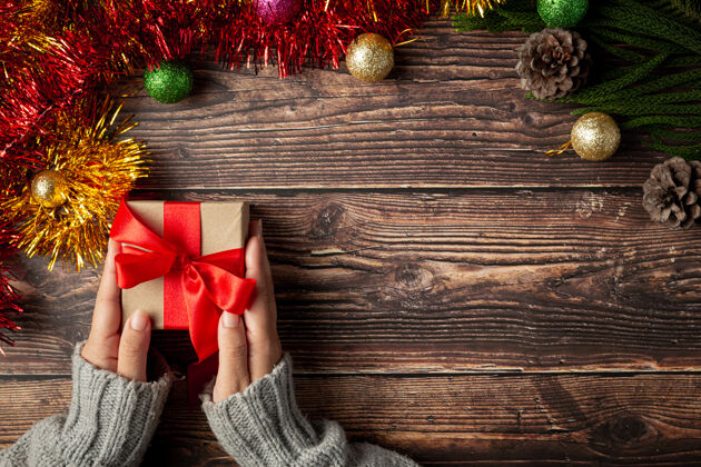 赠送女人的手拿着木地板上的红丝带礼盒圣诞物体蝴蝶结