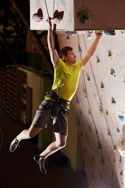攀岩在室内的岩壁上练习攀岩的人肌肉人能量