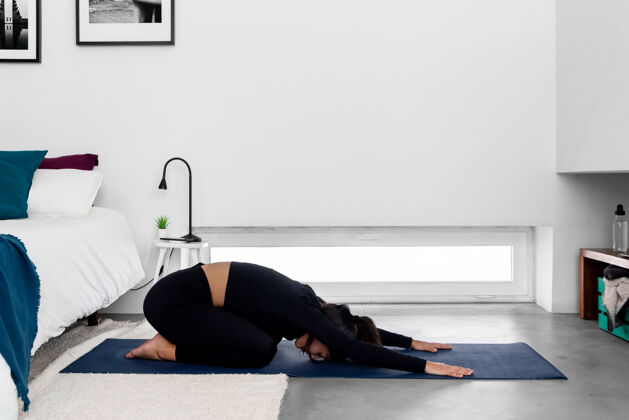 健康年轻苗条的女人在家里的现代简约卧室里练习瑜伽姿势健康力量