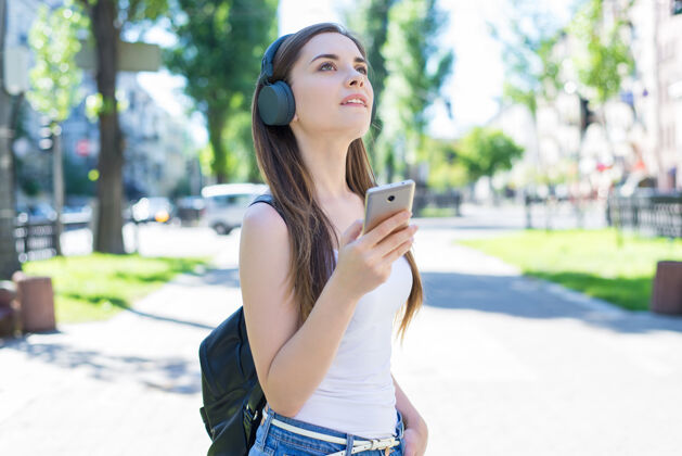 音乐现代科技小工具教育学产生的概念快乐沉思梦幻女士的肖像手持用户手机手持黑色背包公园小镇说话手机漫步