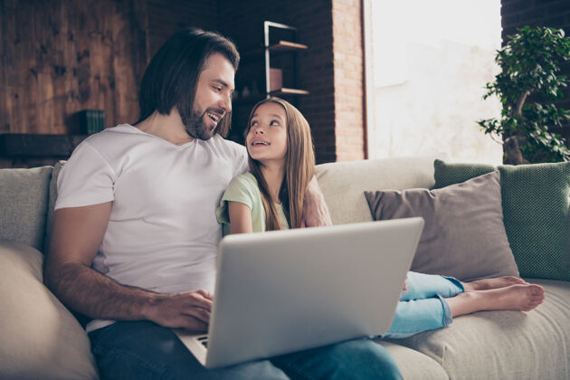 电脑美丽可爱的小女孩和英俊年轻的爸爸坐在舒适的沙发上的照片在线朋友爸爸