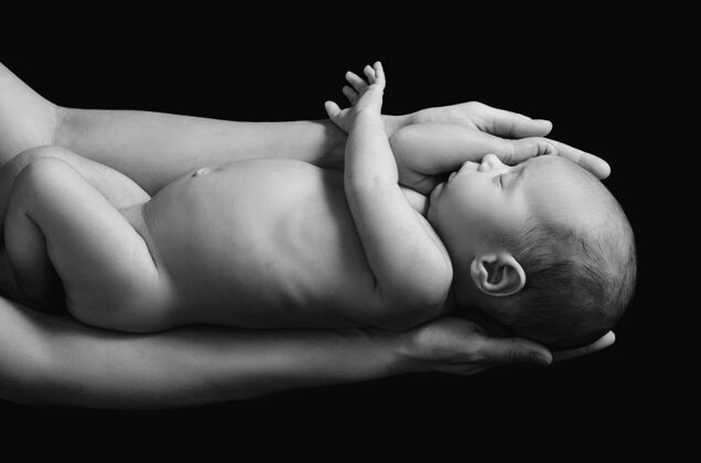 家庭可爱的新生婴儿在妈妈的手上贴着黑墙搞笑睡眠支持
