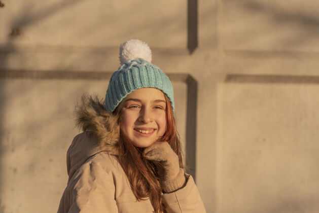 可爱冬天穿米色夹克的女孩一个戴着白色帽子 穿着冬天暖和衣服的蓝色女孩孩子美丽年轻