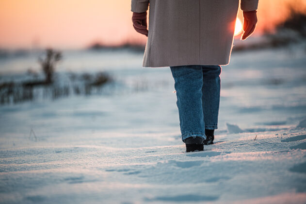 日落日落时分 在冬天的乡下 在新鲜的白雪上 收割着一个穿着暖和的衣服和靴子 面目全非的女人方式女人痕迹