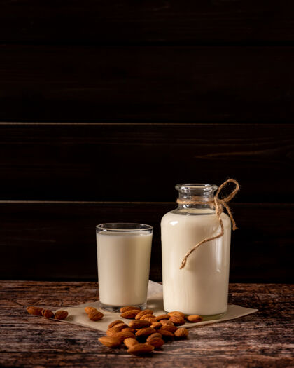 植物蛋白杏仁牛奶装在一个瓶子和一个玻璃杯里 在深色复古木背景上 有复制空间乡村健康习惯低调