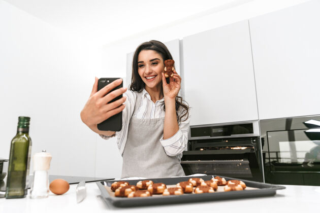 美味迷人的年轻女子站在厨房自拍时 正在托盘上做美味的饼干年轻自拍手机