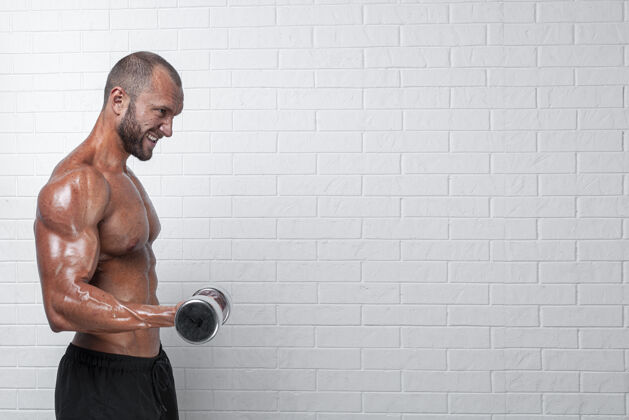 砖墙健美运动员在砖墙上用哑铃练习二头肌肌肉姿势健美