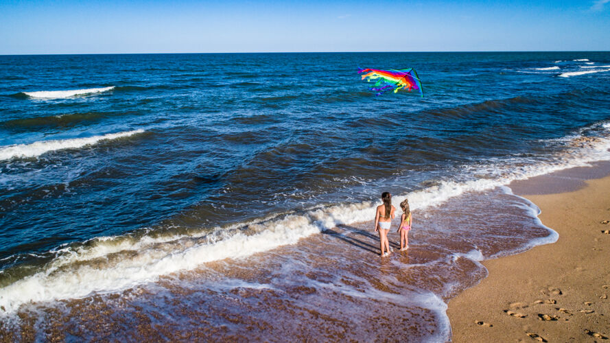 沙滩两个女孩在海边玩风筝海浪慢跑沙滩
