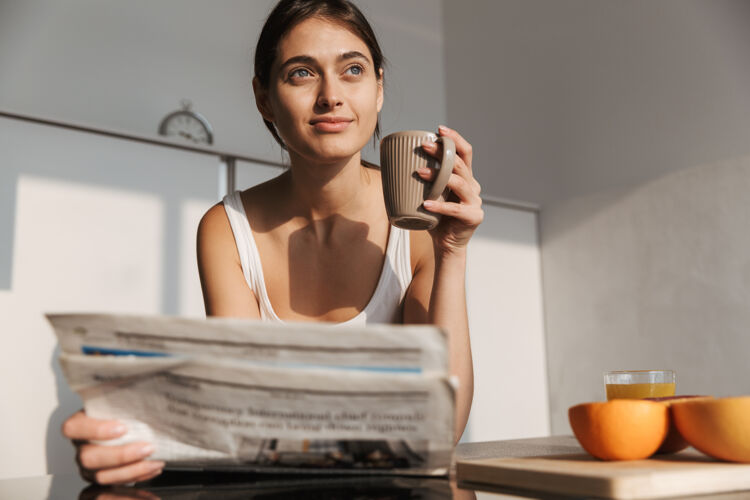 咖啡微笑的年轻女孩早上站在厨房 看报纸 喝茶阅读美味快乐