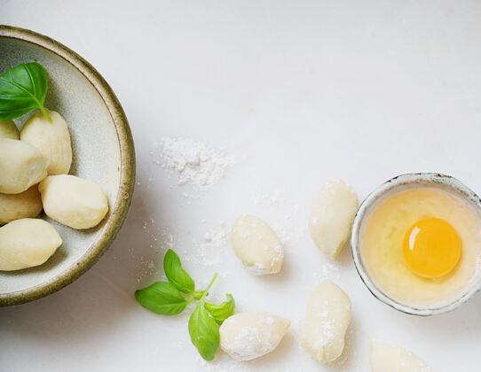 传统传统的意大利土豆面食 用罗勒叶 鸡蛋 面粉装饰生面概念顶视图平躺烹饪手工制作意大利面食