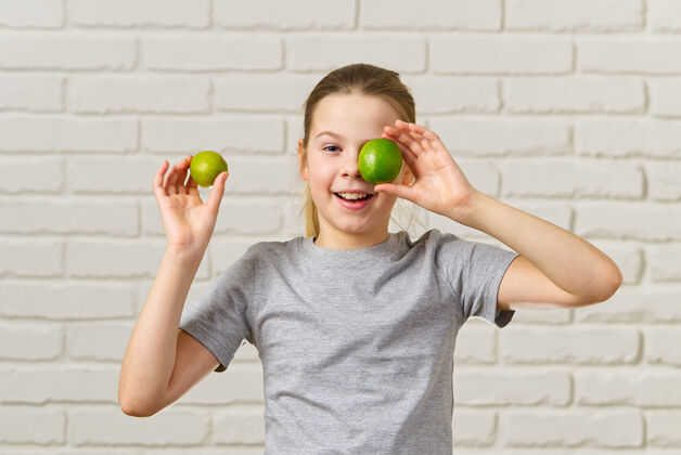 有趣快乐的女孩有乐趣和覆盖她的眼睛与石灰 健康饮食 有机食品 水果饮食 概念饮食青少年夏天