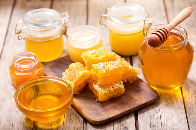 食品各种各样的蜂蜜放在木桌上的玻璃罐里罐子液体产品